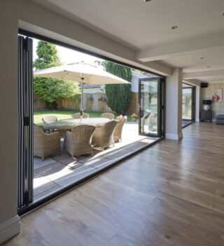 Large bifold doors opening up to a patio with rattan furniture